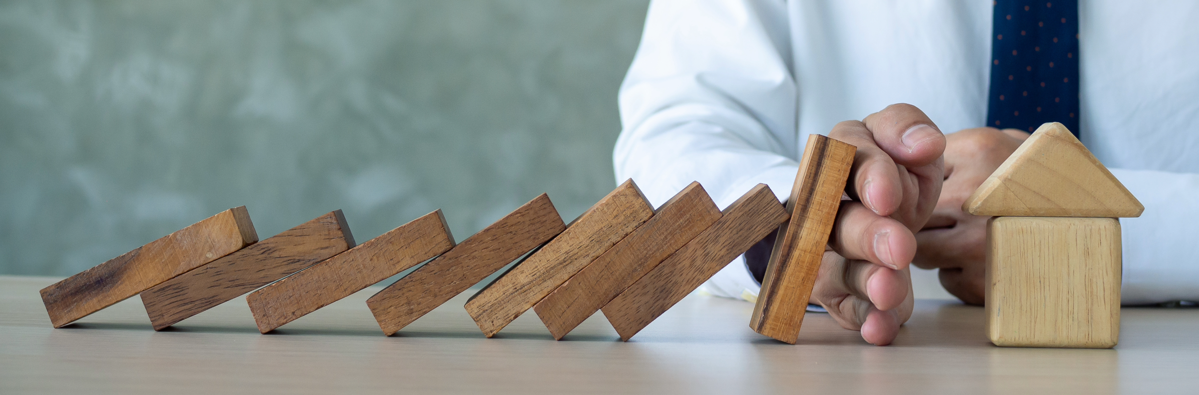 Business continuity, expressed by domino blocks tipping over and stopped by a hand